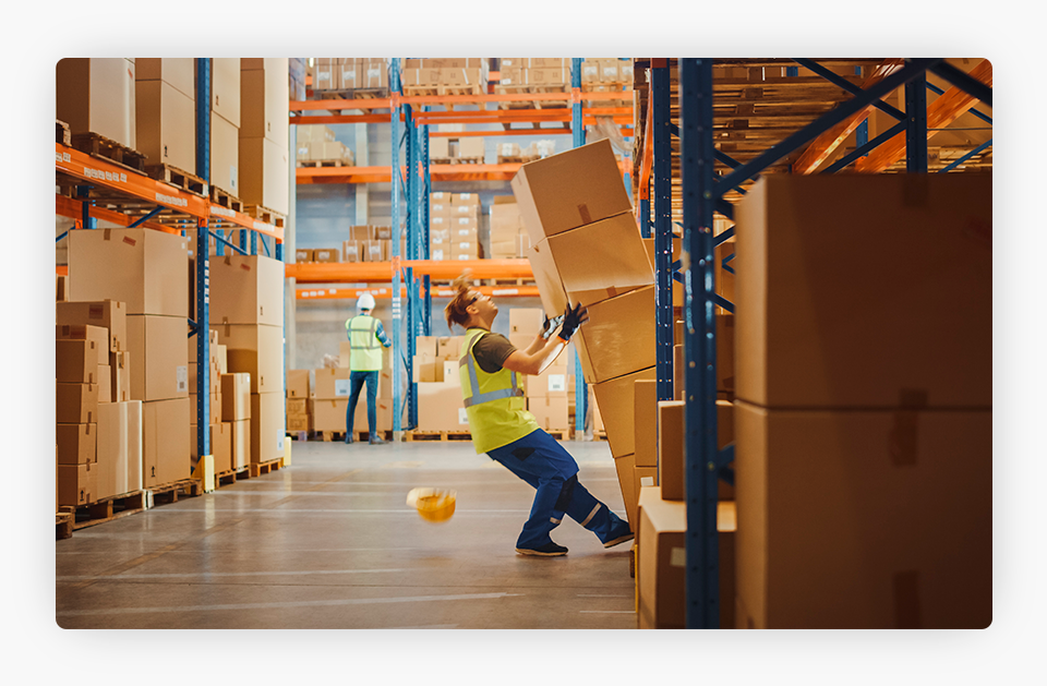 Worker falling with stacked boxes in a warehouse