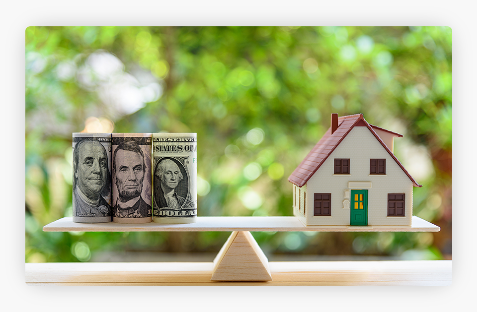 House model and US dollars on a balance scale